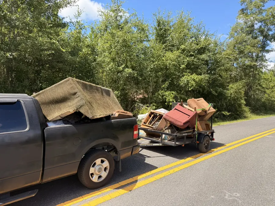 Truck and trailer hauling away old couches and furniture from a Florida Panhandle home